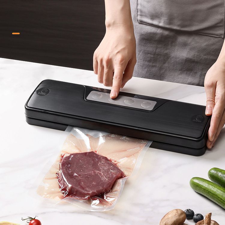 Vacuum sealer in use, hands placing a sealed food bag on a counter