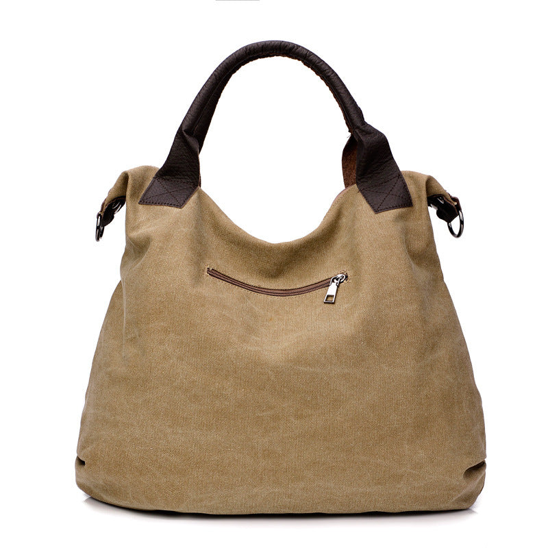 Beige canvas hobo shoulder bag with dark handles and crossbody strap, front zipper pocket