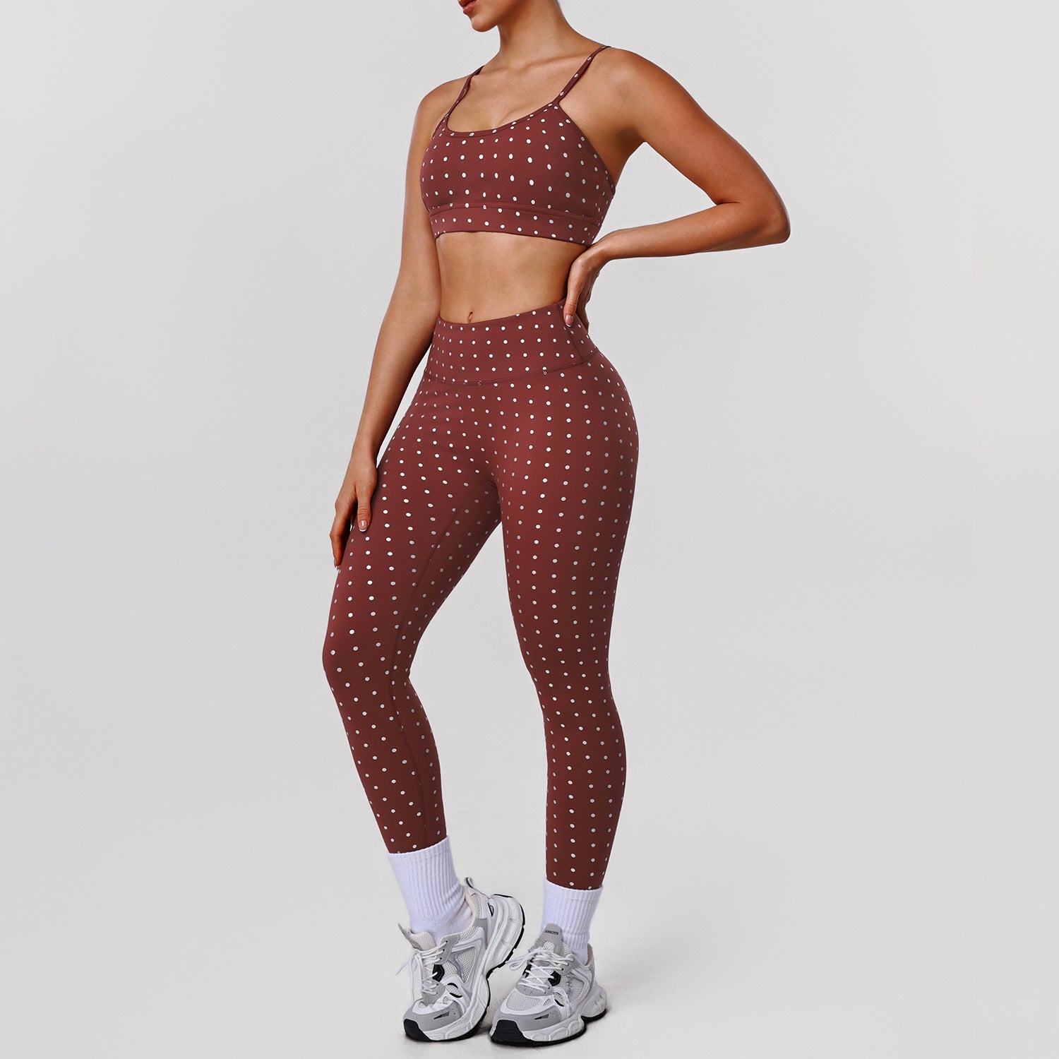 Women’s rust red sports bra and workout pants set with white dot print, side view