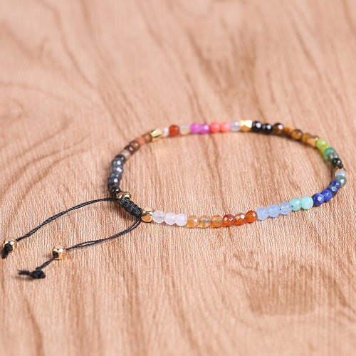 Seven chakras colored stones bracelet laid flat, multicolor beads with tied cord ends