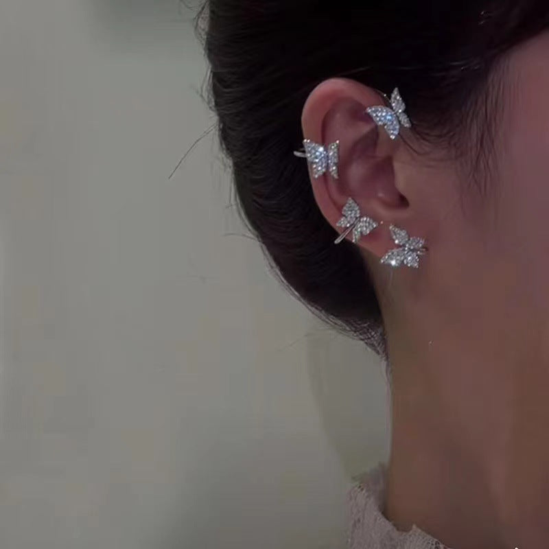 Silver butterfly ear cuff on ear with three glitter butterfly charms visible