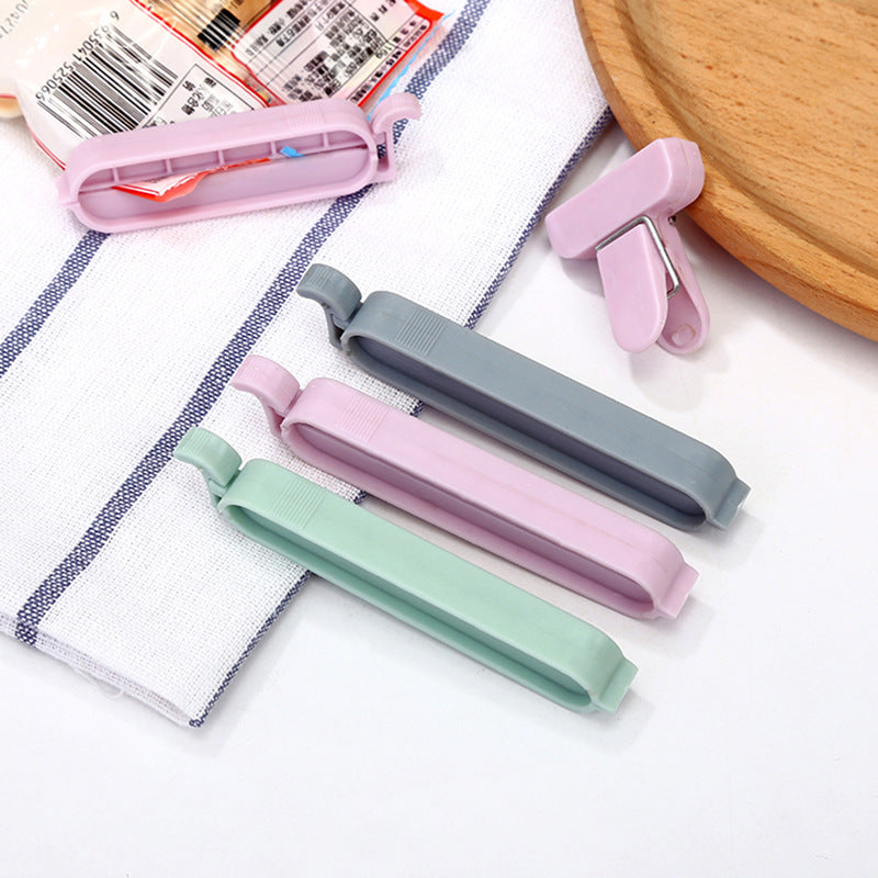Pastel plastic bag sealing clips on fabric, pink, lavender, mint, and gray