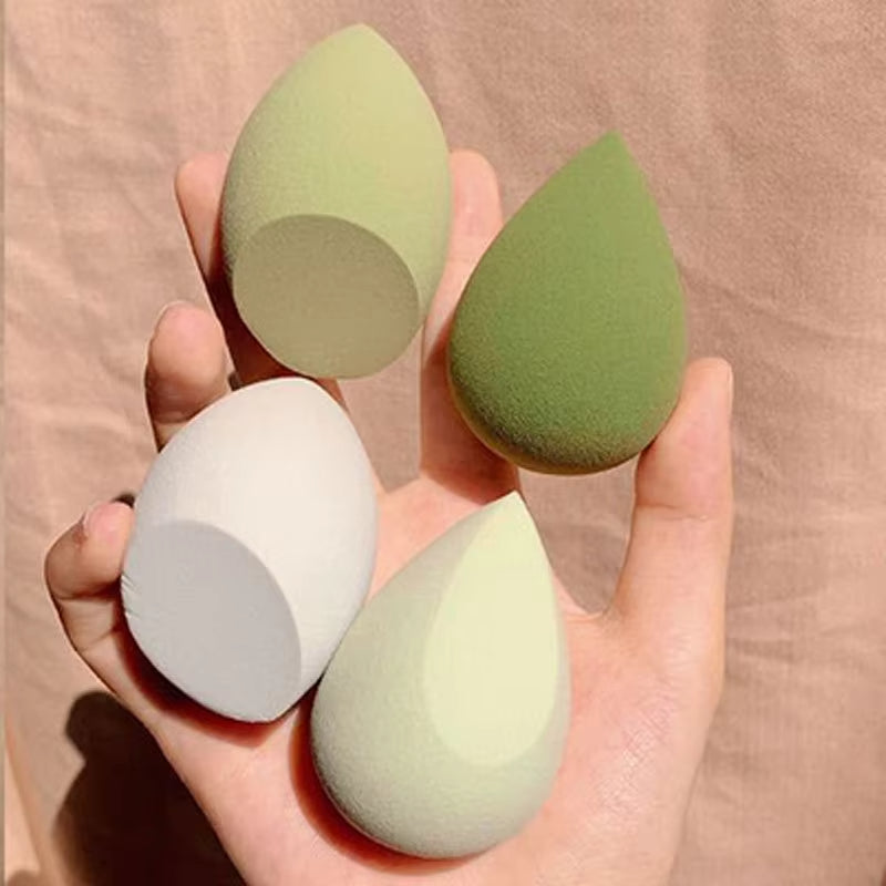 Teardrop makeup sponges in green and white tones, held in hand