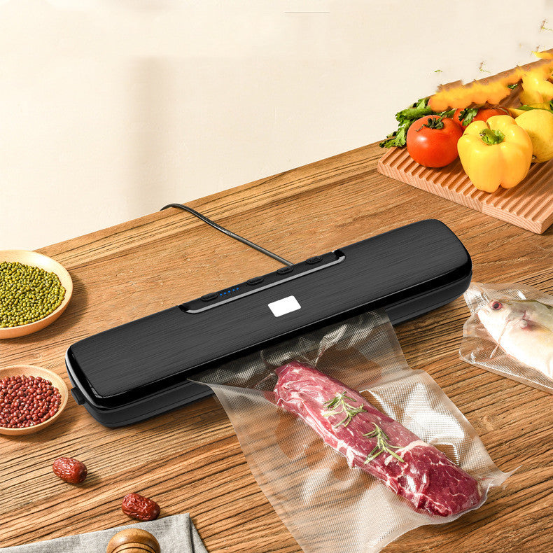 Black vacuum food sealer with a vacuum bag of meat on a wooden countertop
