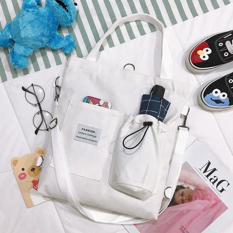 White canvas tote bag with front pocket and drawstring, plaid patch detail